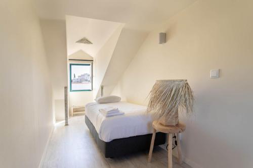 a small white bedroom with a bed and a stool at Vila Santa Marinha in Lisbon