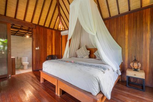 a bedroom with a bed with a mosquito net at NILUH Private Villas Ubud in Ubud