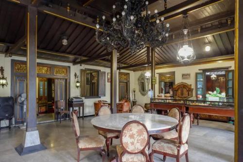 a dining room with a table and chairs and a chandelier at Cakra Homestay Solo Mitra RedDoorz in Solo