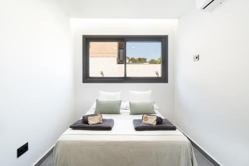 Cama en habitación blanca con ventana en Altafulla Piscina 4BD Beach BBQ Wifi Portaventura en La Riera