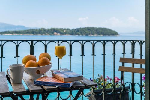 einen Tisch mit einer Schale Obst und einem Glas Orangensaft in der Unterkunft Fotiadis Family Luxury Suites by Konnect in Korfu-Stadt
