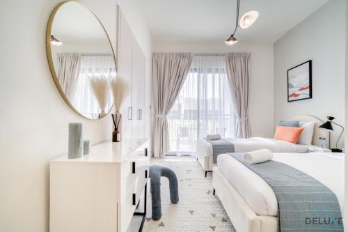 a white bedroom with two beds and a mirror at Spectacular 3BR Townhouse with Assistant Room and Private Pool at DAMAC Hills 2 Dubailand by Deluxe Holiday Homes in Dubai