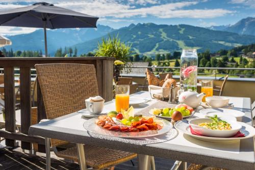 una mesa con un plato de comida en el balcón en Hotel Berghof, en Ramsau am Dachstein