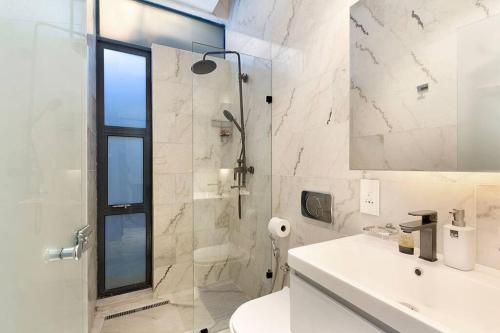 a white bathroom with a shower and a sink at Kalkbay Harbour Retreat in Cape Town