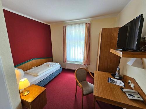 ein Hotelzimmer mit einem Bett und einem TV in der Unterkunft GreenLine Ferienhotel Forelle in Thale