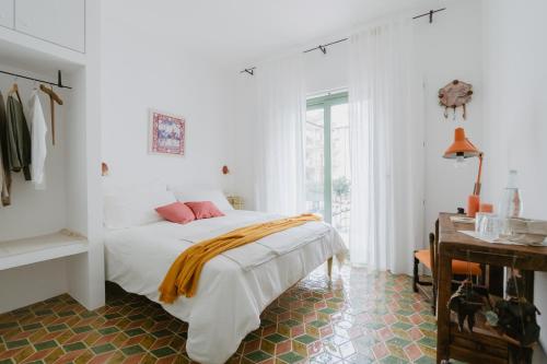 a white bedroom with a bed and a window at Casa Astura in Capo dʼOrlando