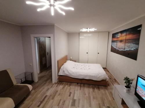 a bedroom with a bed and a couch and a television at Jurmala Kauguri in Jūrmala