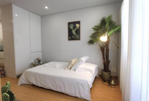 Un dormitorio con una cama blanca y una palmera en OÁSIS apartments, en Viana do Castelo