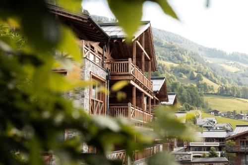 un grande edificio in legno con montagne sullo sfondo di Wildkogel Resorts - DAS Bramberg a Bramberg am Wildkogel