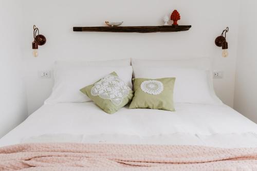 a bedroom with a white bed with two pillows at Casa Astura in Capo dʼOrlando