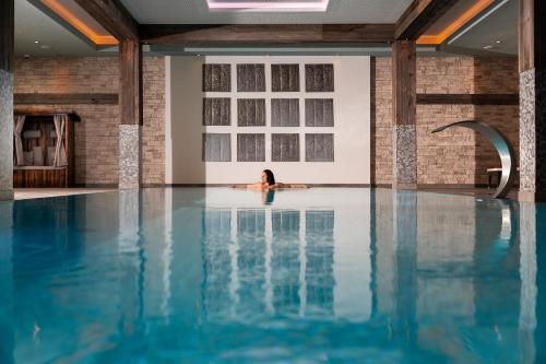 Eine Frau, die in einem Pool in einem Gebäude schwimmt. in der Unterkunft Wildkogel Resorts - DAS Bramberg in Bramberg am Wildkogel