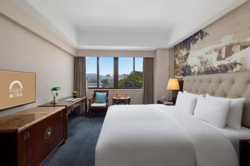 a hotel room with a large bed and a desk at City Hotel Xiamen-Free Welcome Fruits in Xiamen