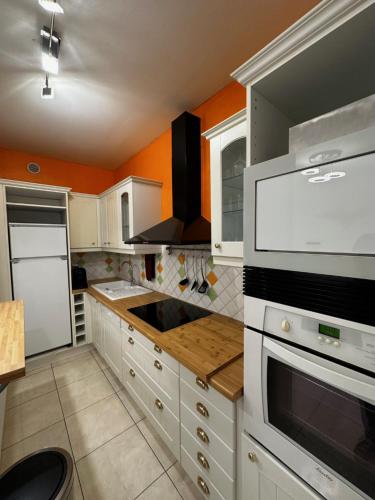 - une cuisine avec des placards blancs et un mur orange dans l'établissement ARENA Center Town, à Reims