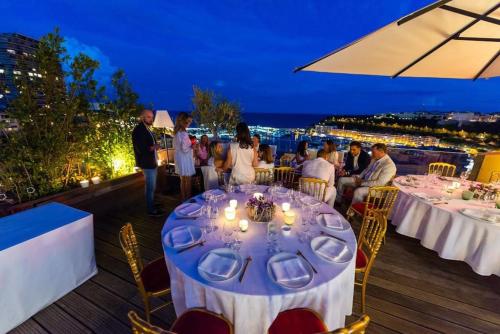 a group of people sitting at tables on a deck at night at Penthouse Roof 6 pieces à Monaco in Monte Carlo
