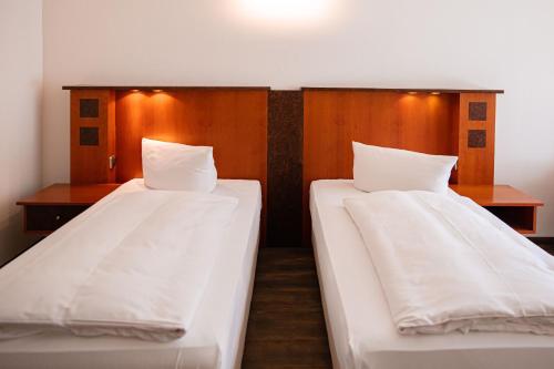 two beds in a room with white sheets at Müggelseeperle in Berlin