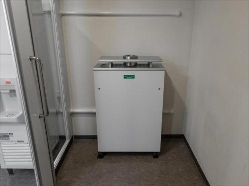 a small white refrigerator in a corner of a room at JR Kyushu Hotel Blossom Fukuoka in Fukuoka