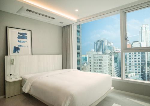 a bedroom with a white bed and a large window at UH FLAT The Seocho in Seoul