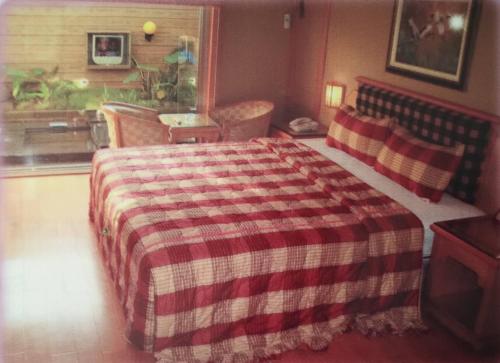 a bedroom with a bed with a checkered blanket at Ai Yi Bao Motel in Toufen