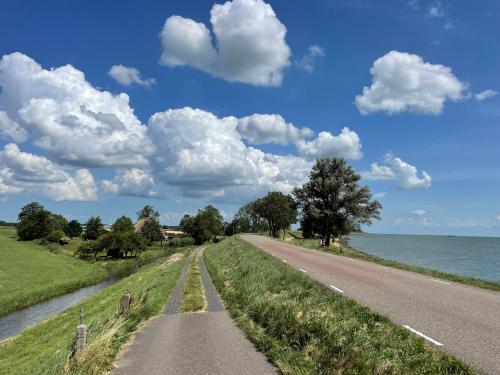Un camino junto al agua con nubes en el cielo en Hotelhuisjes Oosterleek, en Oosterleek