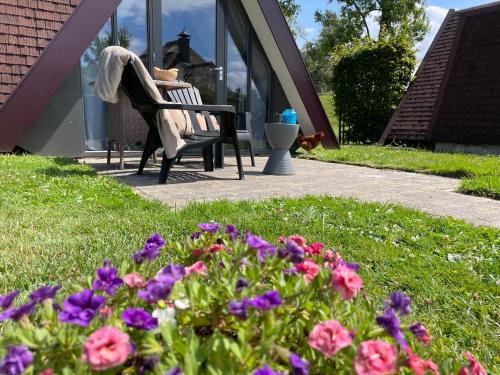 Hotelhuisjes Oosterleek في Oosterleek: مقعد في حديقة بها زهور أمام المبنى