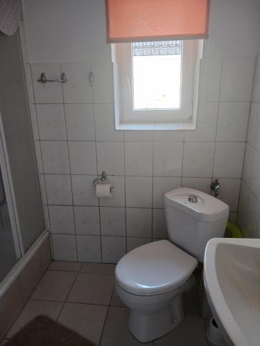 a bathroom with a toilet and a sink and a window at Apartament w cichej dzielnicy in Kołobrzeg