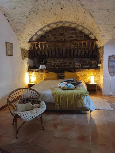 een slaapkamer met een bed en een stoel in een kamer bij Magnanerie du Perrier : studio indépendant au pied des Cévennes in Pompignan