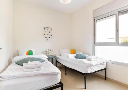 dwa łóżka w pokoju z oknem w obiekcie Yama SEA VIEW 4BR w mieście Naharijja