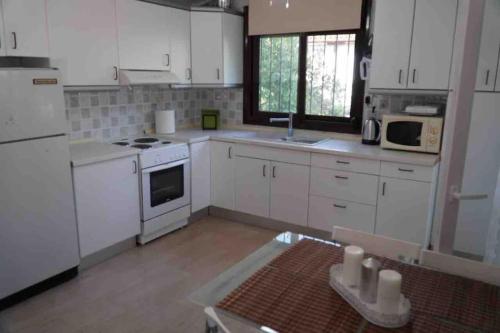 a kitchen with white cabinets and white appliances at Karipidis houses in Nea Iraklia