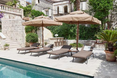 a group of chairs and umbrellas next to a pool at Villa Perastian Thriton in Perast