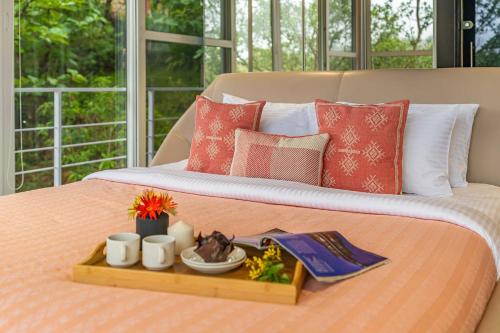 bandeja de comida encima de la cama en The Glasscape by StayVista - Hillside getaway with Pool and Indoor games, en Nashik