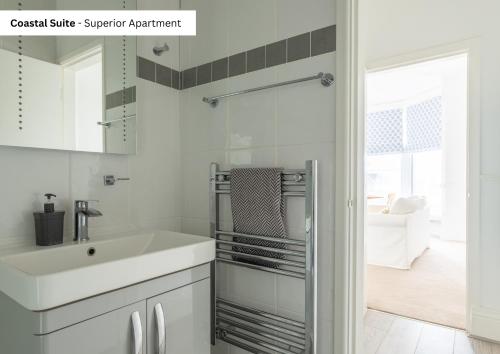 een witte badkamer met een wastafel en een spiegel bij The Chymes Holiday Flats in Lytham St Annes
