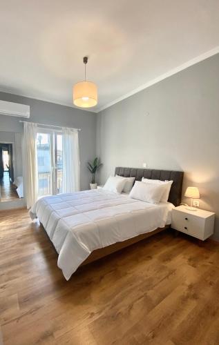- un grand lit blanc dans une chambre avec une grande fenêtre dans l'établissement Makao Apartment corfu, à Corfou