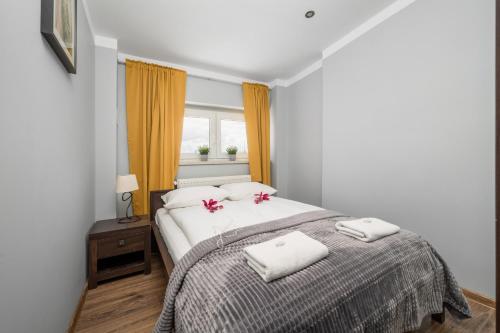a bedroom with a bed with two white towels and a window at Market Square Corner Apartment Kuźnicza by Renters in Wrocław