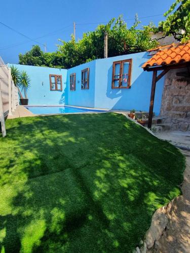 un patio con una casa azul con césped verde en Casa da Poça, en Baião