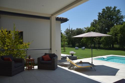 eine Terrasse mit 2 Stühlen, einem Sonnenschirm und einem Pool in der Unterkunft Ici et Là - Chambres d'hôtes in Velleron