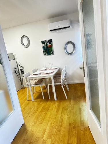 a white dining room with a white table and chairs at Family Apartman in Donji Milanovac