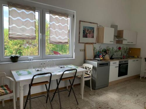 a kitchen with a white table and chairs and two windows at Wohlfühloase auf 133-160qm in der Idylle an der Nahe in Duchroth