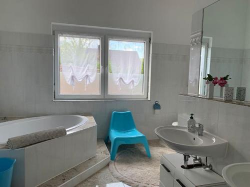 a bathroom with a tub and a sink and a blue chair at Wohlfühloase auf 133-160qm in der Idylle an der Nahe in Duchroth