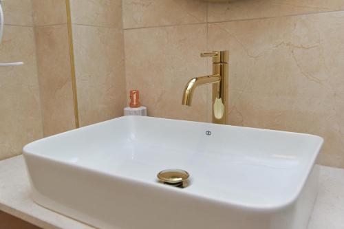 a white sink with a gold faucet in a bathroom at Apartments Jelušić in Budva