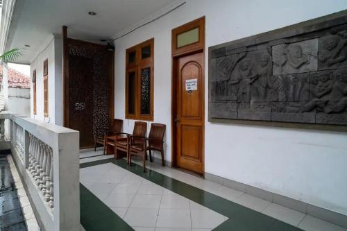 a hallway of a building with a wooden door and chairs at Puri Saras Bintaro Syariah Mitra RedDoorz in Jurangmanggu