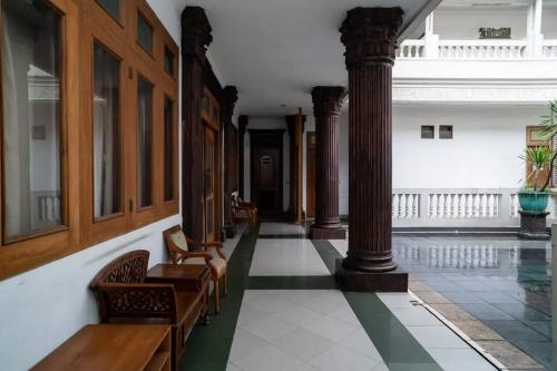 a hallway with chairs and columns in a building at Puri Saras Bintaro Syariah Mitra RedDoorz in Jurangmanggu