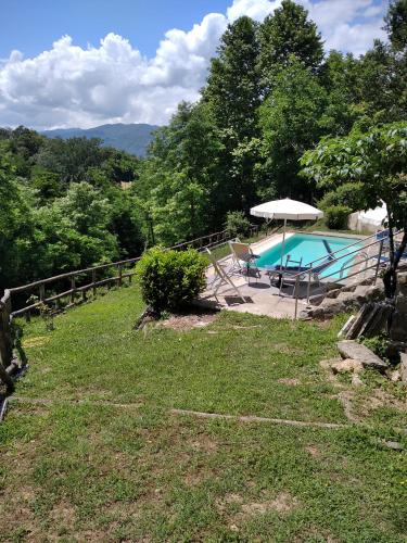 a pool with a table and an umbrella next to it at Villa Belvedere in Pieve Fosciana