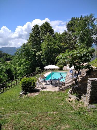 a swimming pool with an umbrella and a house at Villa Belvedere in Pieve Fosciana