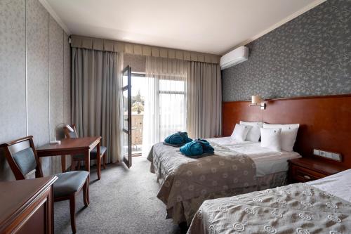 a hotel room with two beds and a desk at Hotel&Spa Stary Dziwnów basen swimming pool in Dziwnów