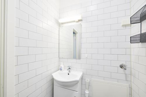 La salle de bains blanche est pourvue d'un lavabo et d'un miroir. dans l'établissement Grünerløkka shared Apartment Rooms, à Oslo