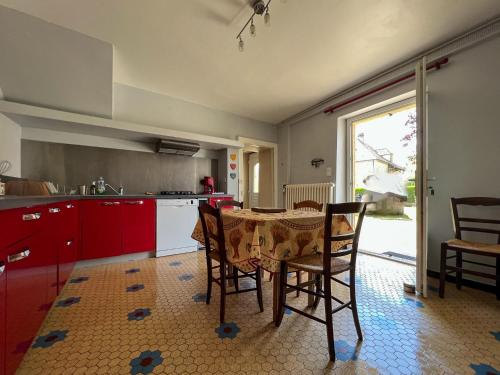 eine Küche mit einem Tisch und Stühlen sowie eine Küche mit roten Schränken in der Unterkunft Maison Sainte-Sabine Castels in Castels