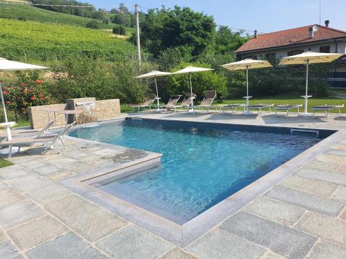 a swimming pool with chairs and umbrellas at Agriturismo Cascina L'Arché in Santo Stefano Belbo