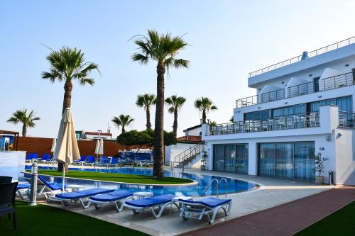 a hotel with a swimming pool and palm trees at Mimoza Beach Hotel in Yenibosazici