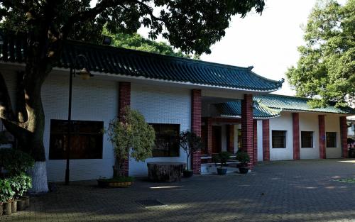 a white building with a tree in front of it at City Hotel Xiamen-Free Welcome Fruits in Xiamen