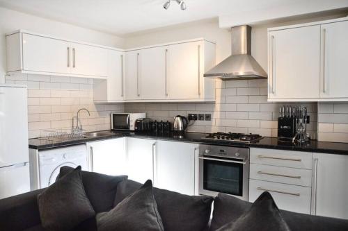 a kitchen with white cabinets and a couch in it at Modern 1 bedroom apartment close to Penzance town centre. in Penzance